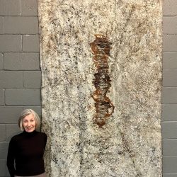 Rose Marie Prins standing next to her painting, “Her Lair: The Topography”