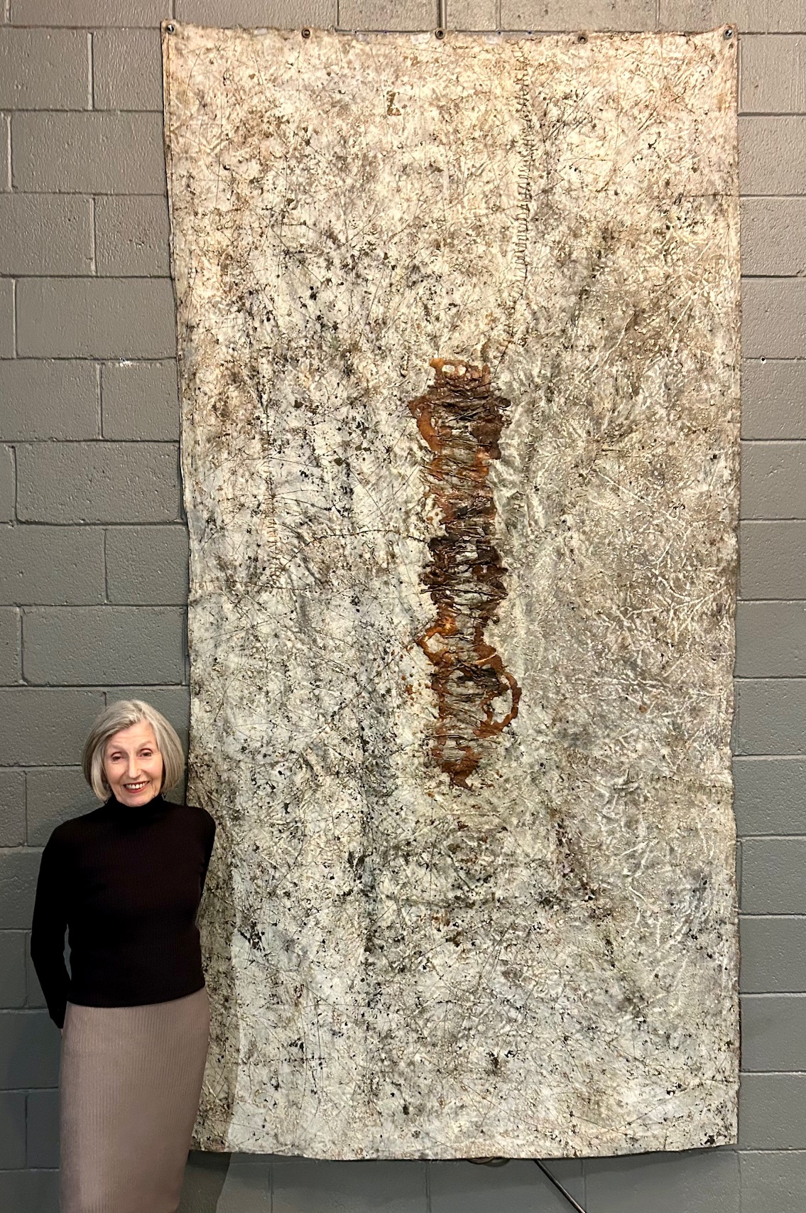 Rose Marie Prins standing next to her painting, “Her Lair: The Topography”